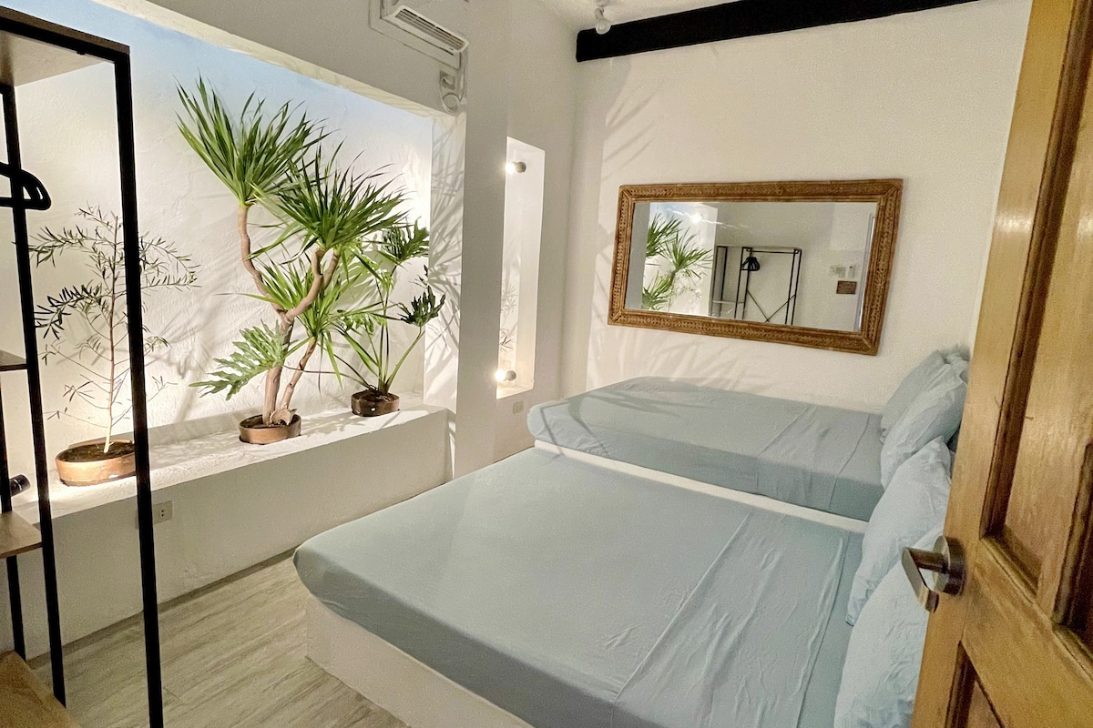 Casa Uno bright bedroom with plants and gold mirror